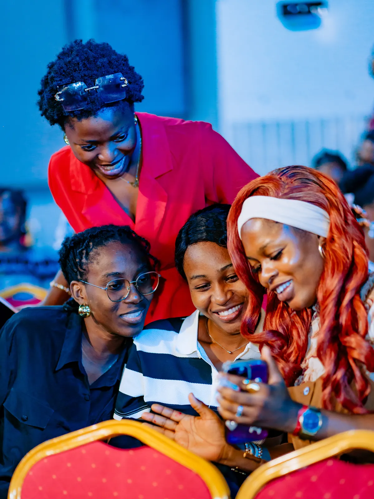 Four attendees smiling and laughing together over a phone at CTC 2.0.